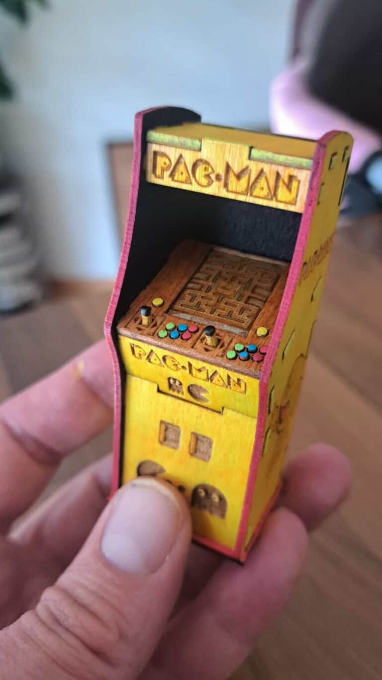 Mini borne d’arcade en bois, gravée et peinte avec détails Pac-Man. Réalisée sur mesure dans notre atelier à Genève.